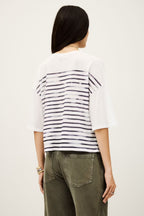 Person wearing a white and black striped shirt and green pants on a plain background