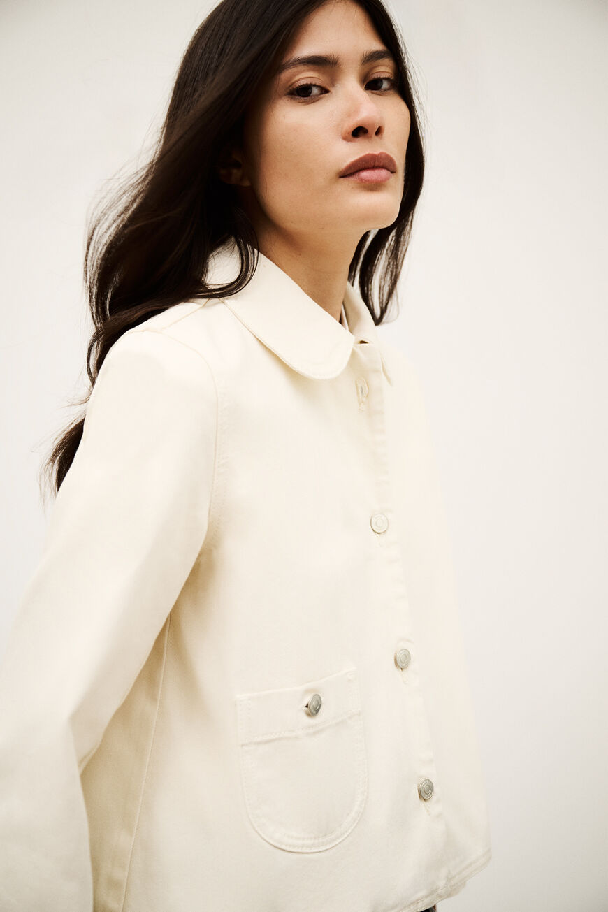 Woman wearing a white button-up shirt against a plain background