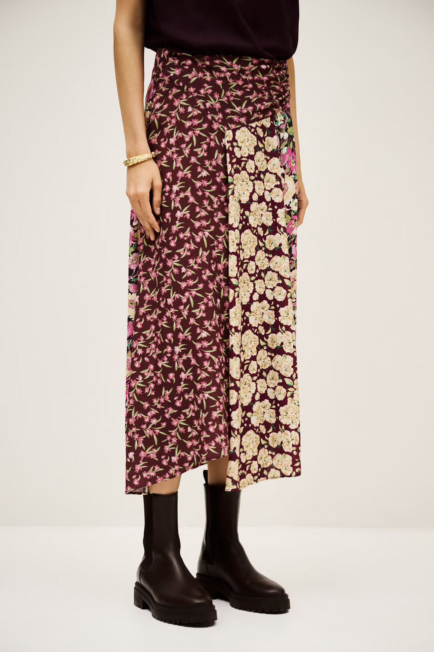 Person wearing a floral skirt with a plain background