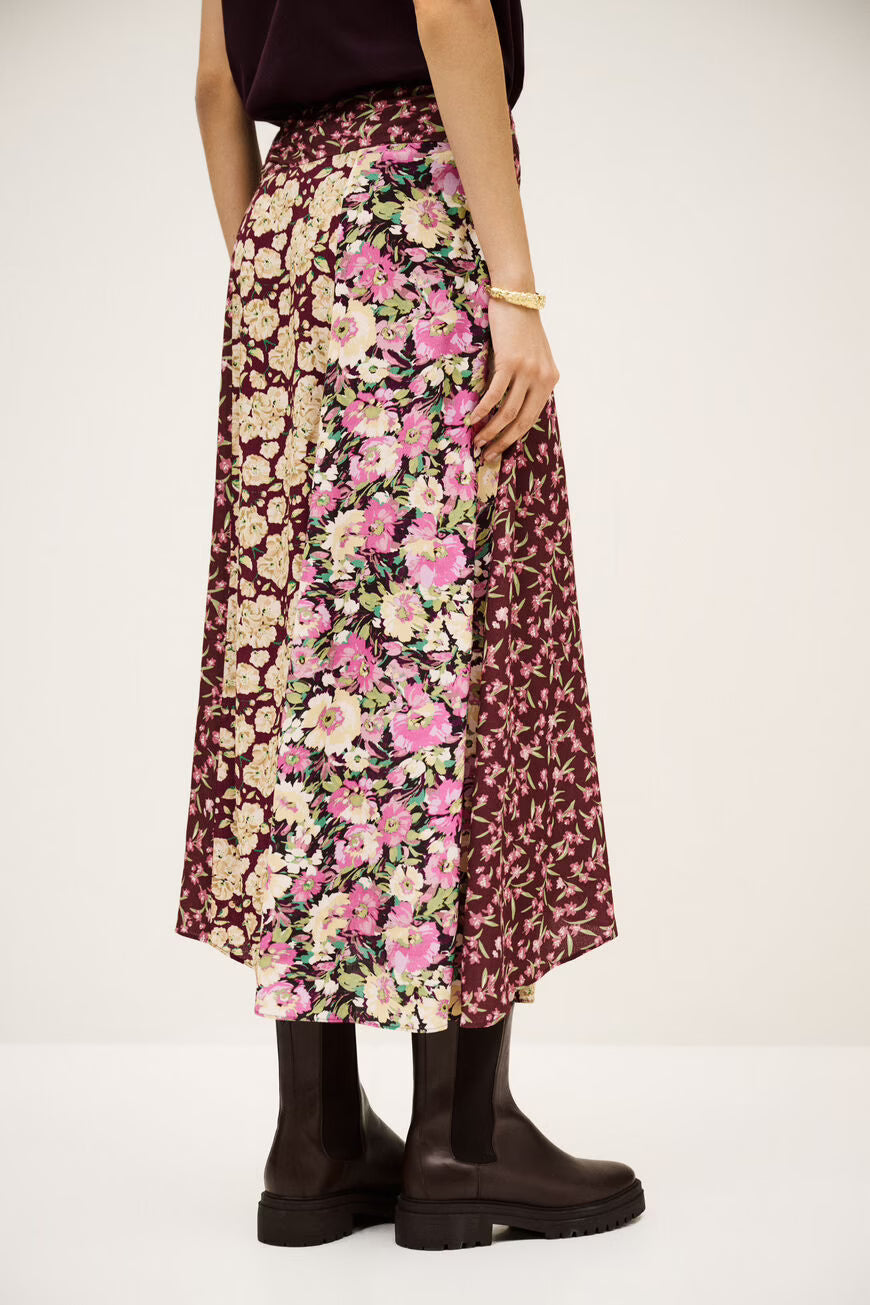 Person wearing a floral skirt with a plain background