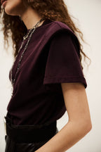 Person wearing a dark purple t-shirt with a neutral background