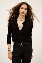 Woman wearing a black outfit with a belt against a plain background