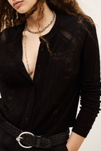 Close-up of a person wearing a black shirt with a necklace and belt.