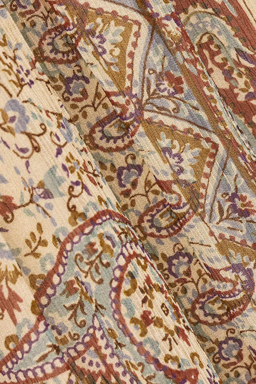 A close-up of a draped fabric with an intricate paisley pattern in muted tones of beige, brown, dusty blue, and purple.