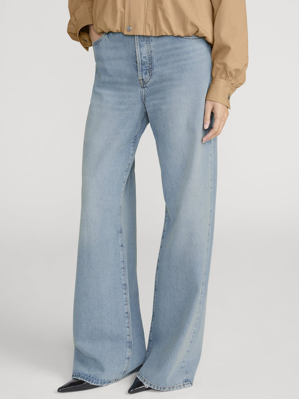Light blue flared jeans worn by a person on a white background