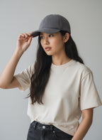 Woman wearing a gray cap and beige t-shirt against a plain background