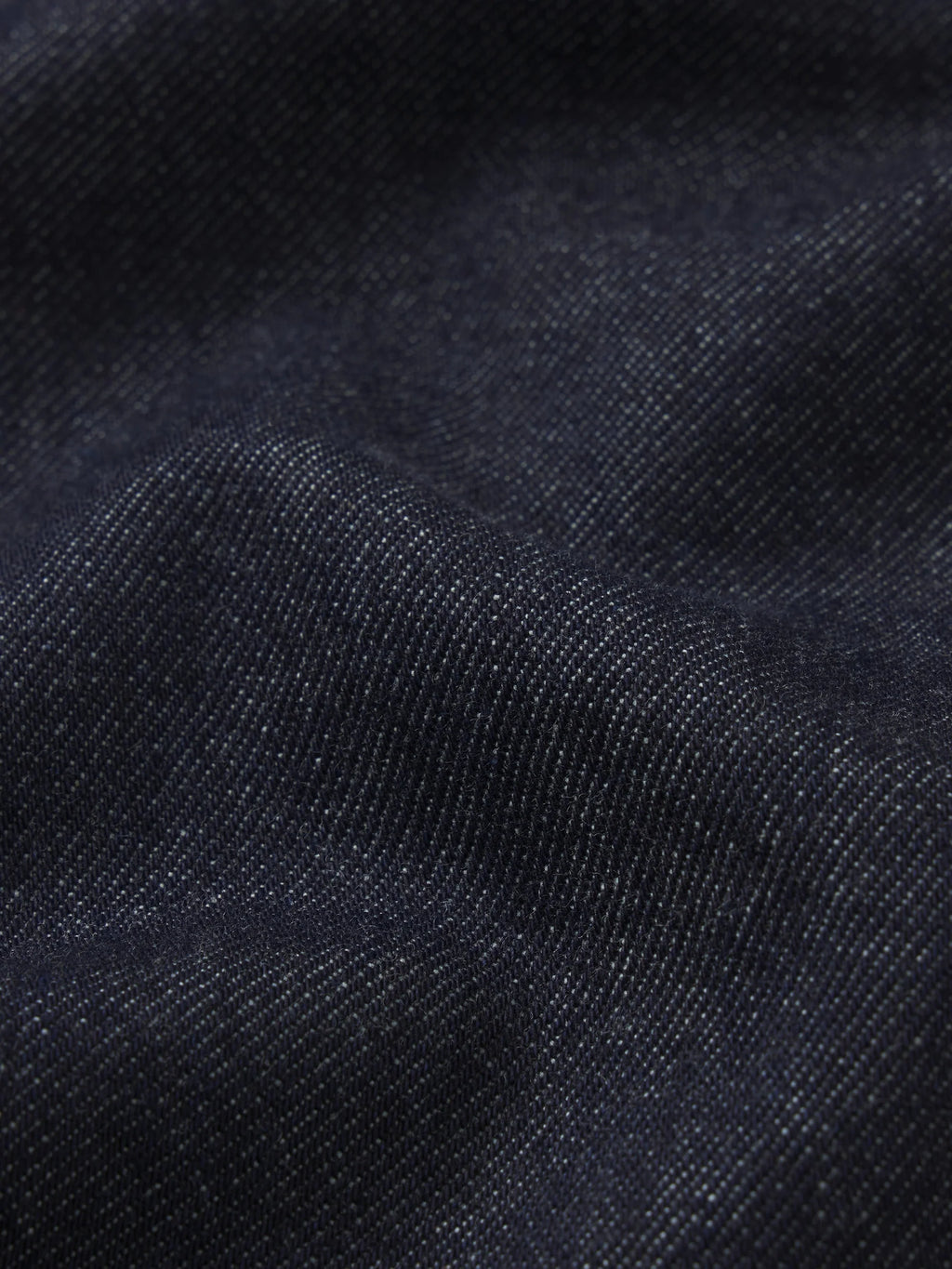 Close-up of dark navy blue textured fabric with a fine woven pattern and soft folds.