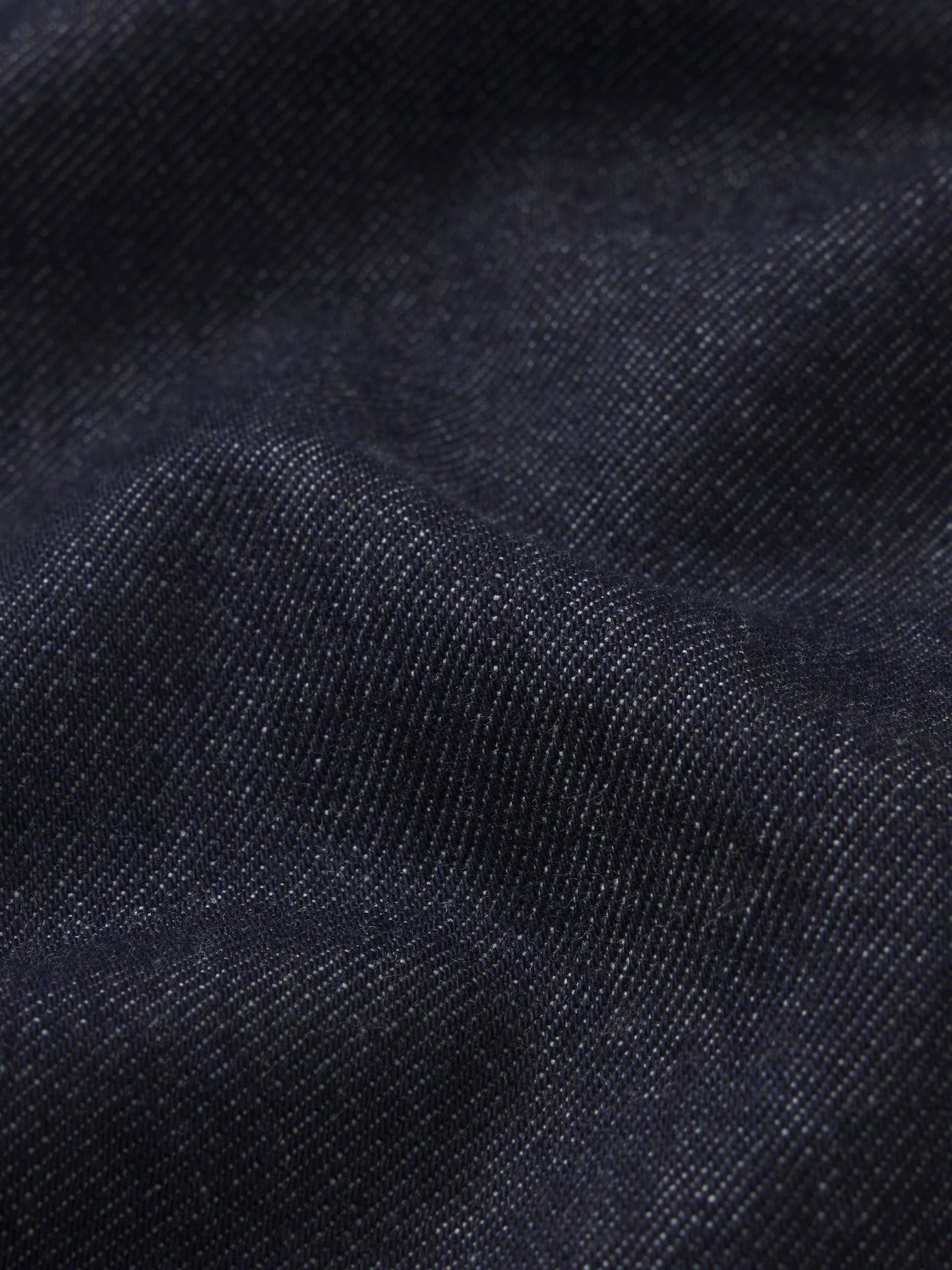 Close-up of dark navy blue textured fabric with a fine woven pattern and soft folds.