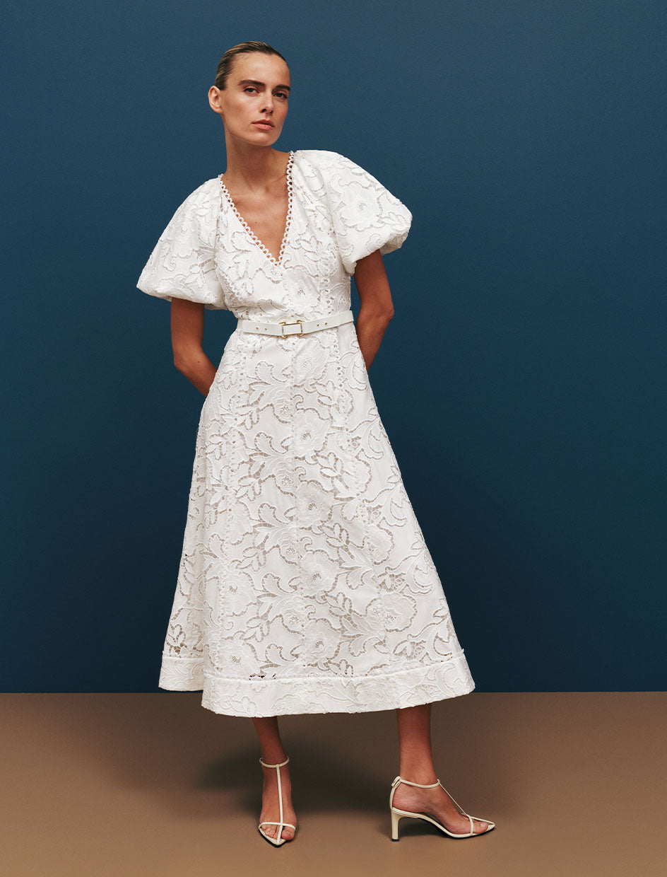 Woman wearing a white lace dress against a blue background