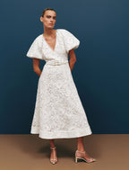 Woman wearing a white lace dress against a blue background