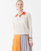 Woman wearing a white sweater with orange accents and a colorful skirt on a white background