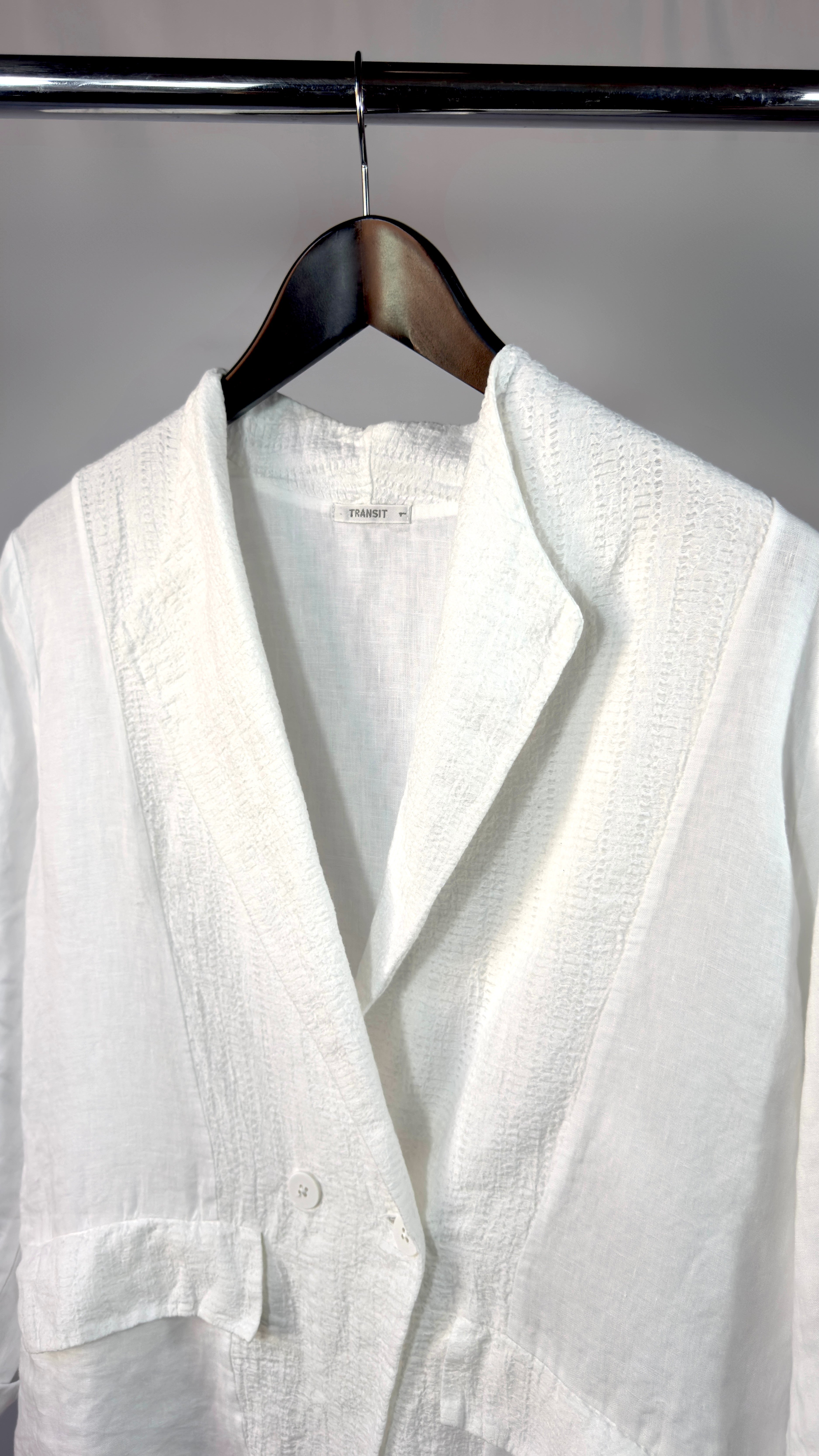 White linen shirt on a hanger against a gray background