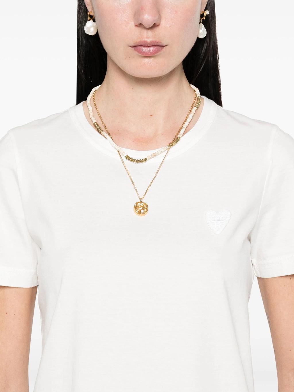 Woman wearing a gold necklace with a pendant on a white background