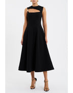 A model wearing a black midi dress with an asymmetrical bodice, A-line skirt, and gold art deco trim.