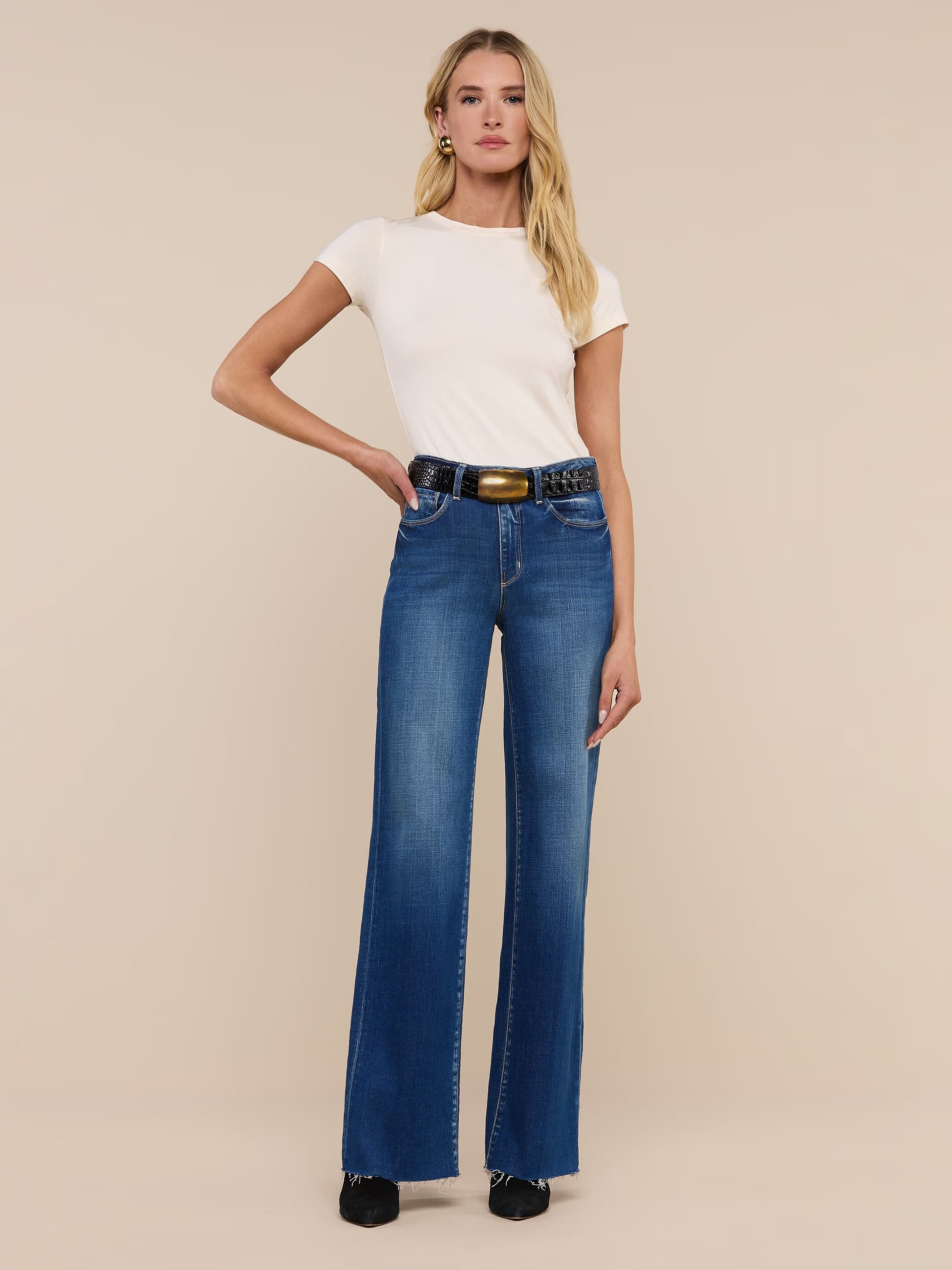 Woman wearing blue jeans and a white top on a beige background. l'agence scottie wide leg jean