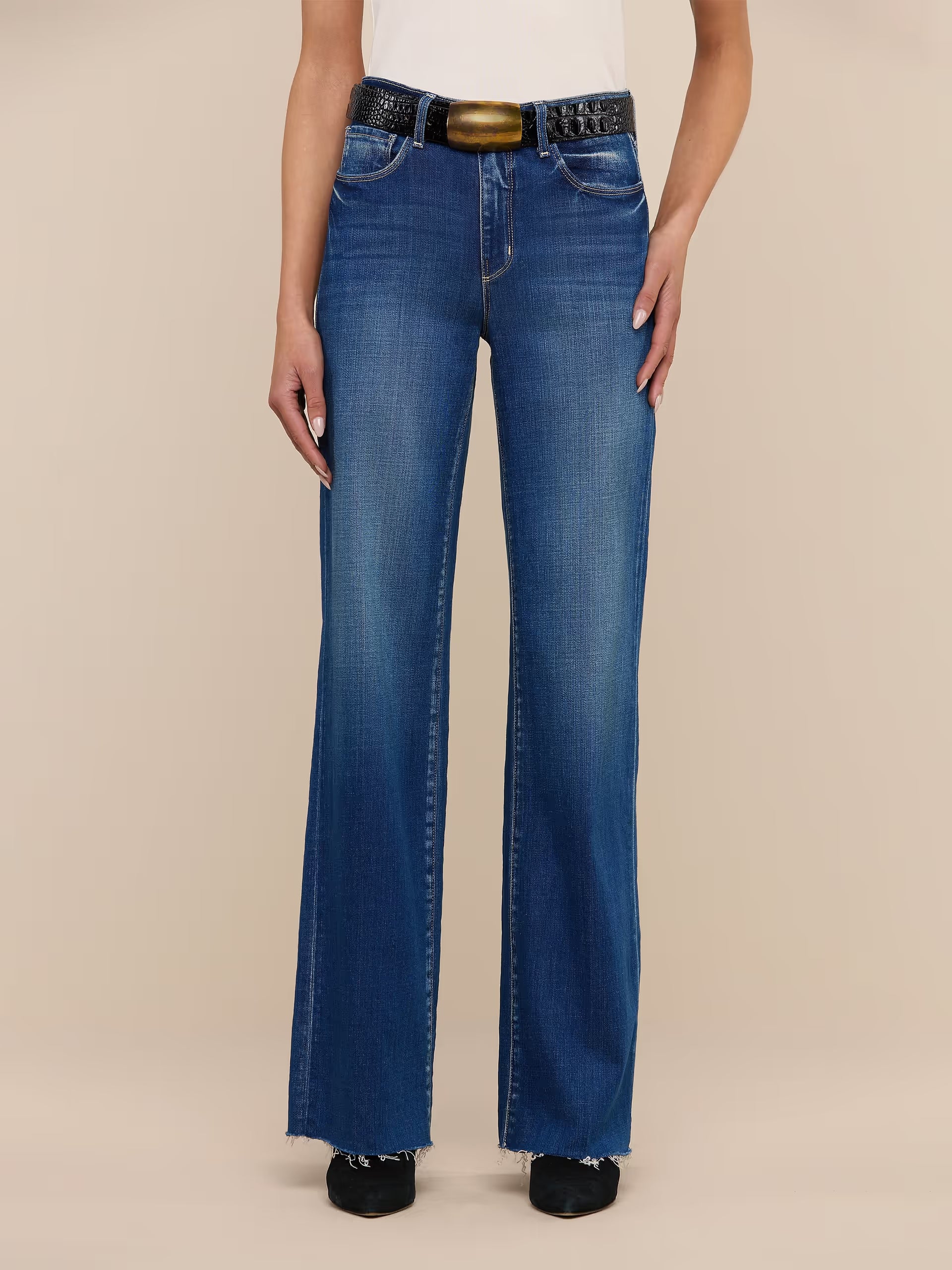Person wearing blue jeans with a belt on a beige background. l'agence scottie wide leg jean 