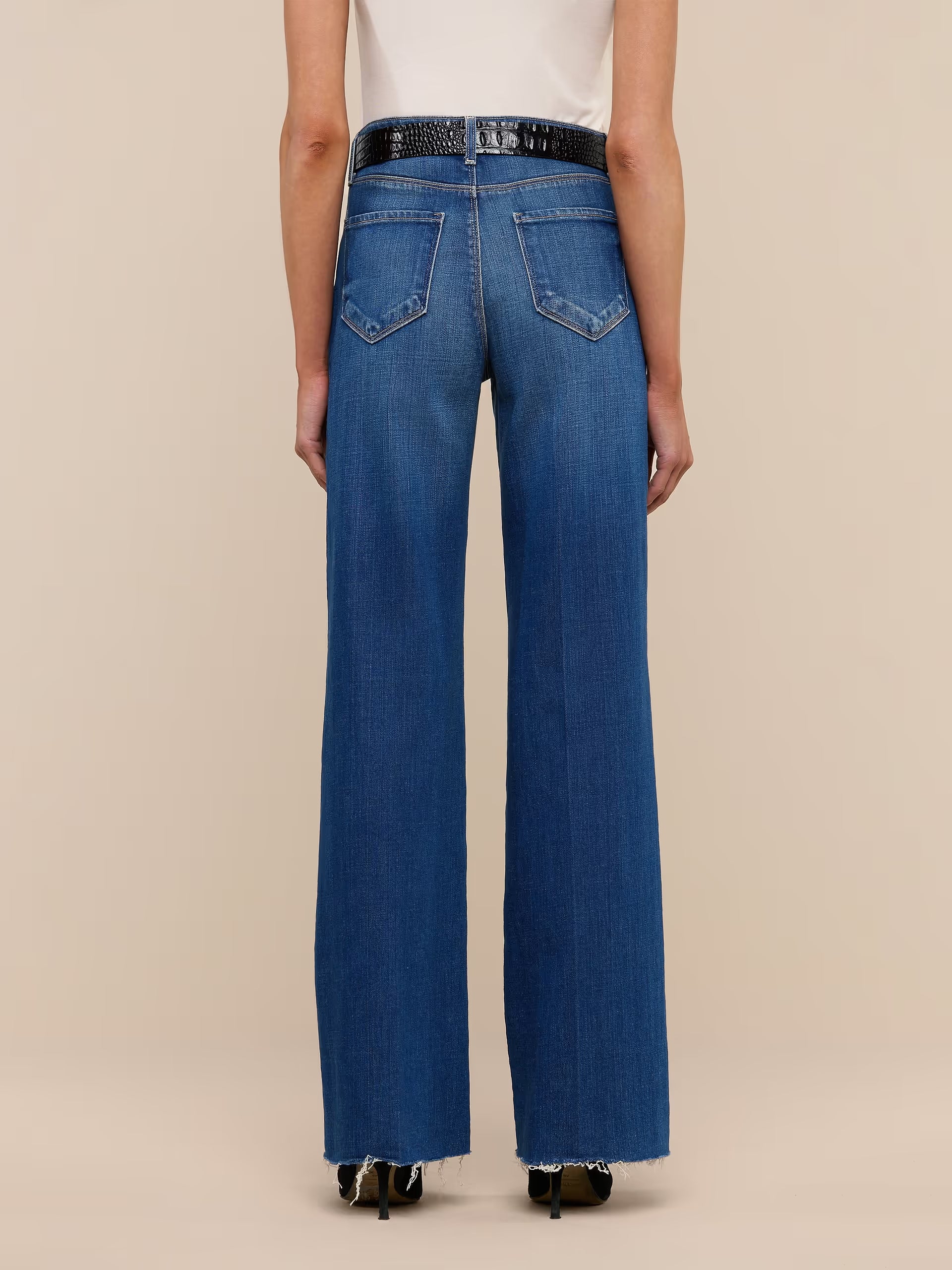 Blue jeans worn by a person on a beige background