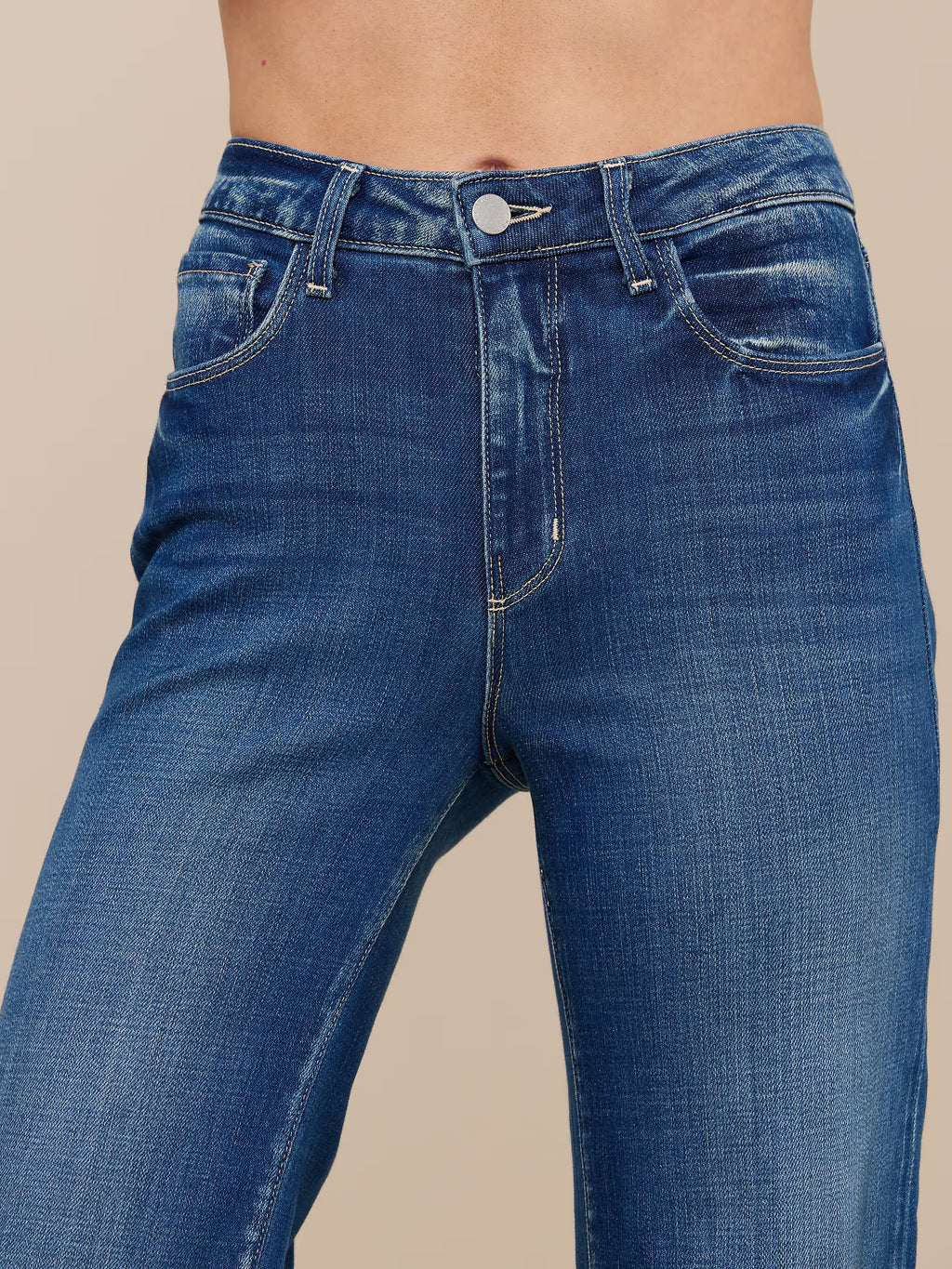 Blue jeans worn by a person on a beige background