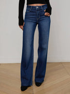 Person wearing blue flared jeans and black top on a plain background