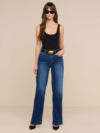 Woman wearing blue jeans and a black tank top on a beige background