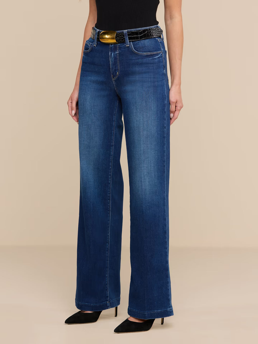 Person wearing blue jeans with a beige background