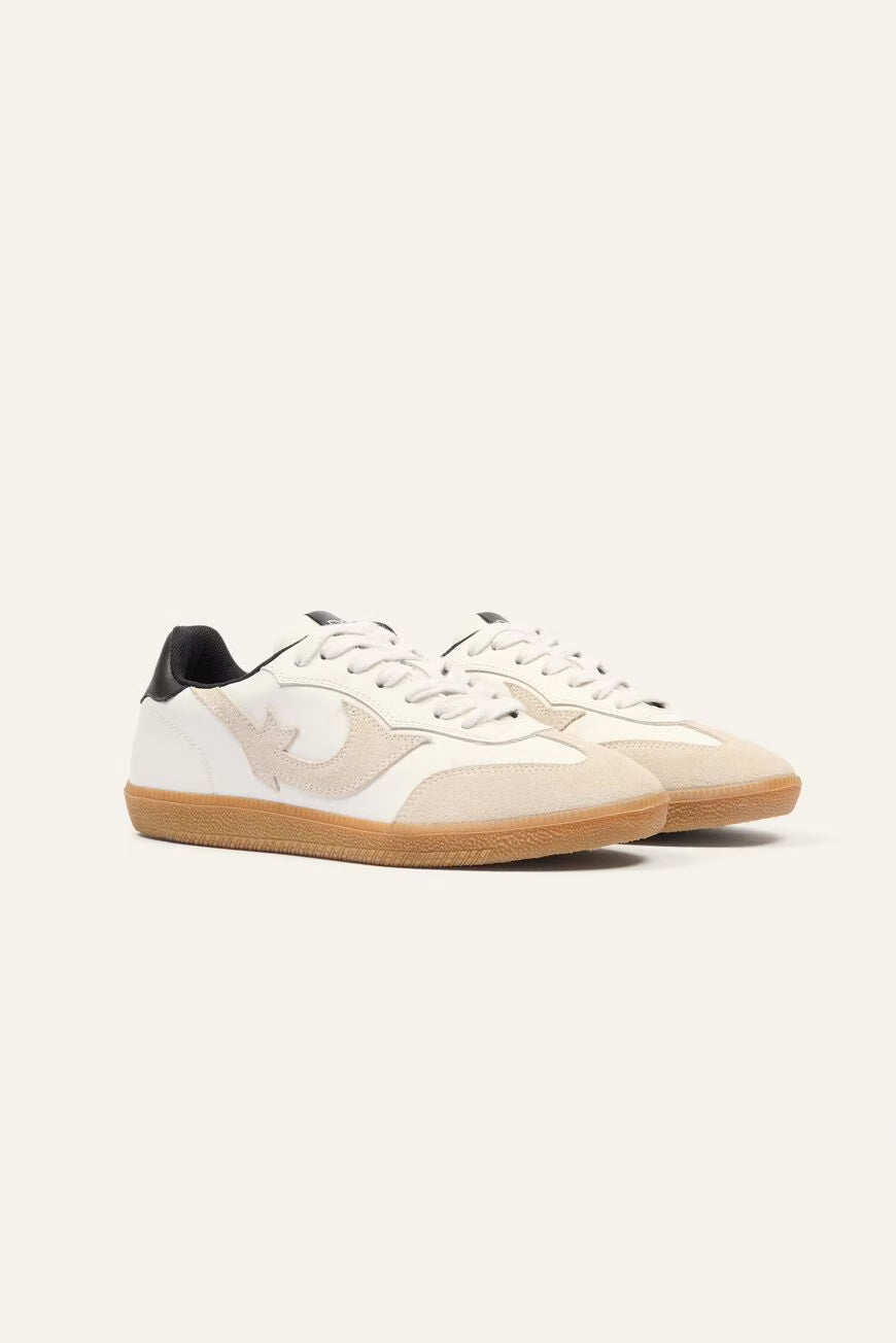 Pair of white sneakers with brown soles on a light beige background