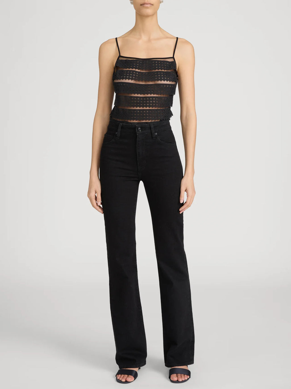 Person wearing a black lace top and black pants on a white background frame the arrow