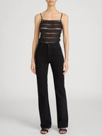 Person wearing a black lace top and black pants on a white background frame the arrow