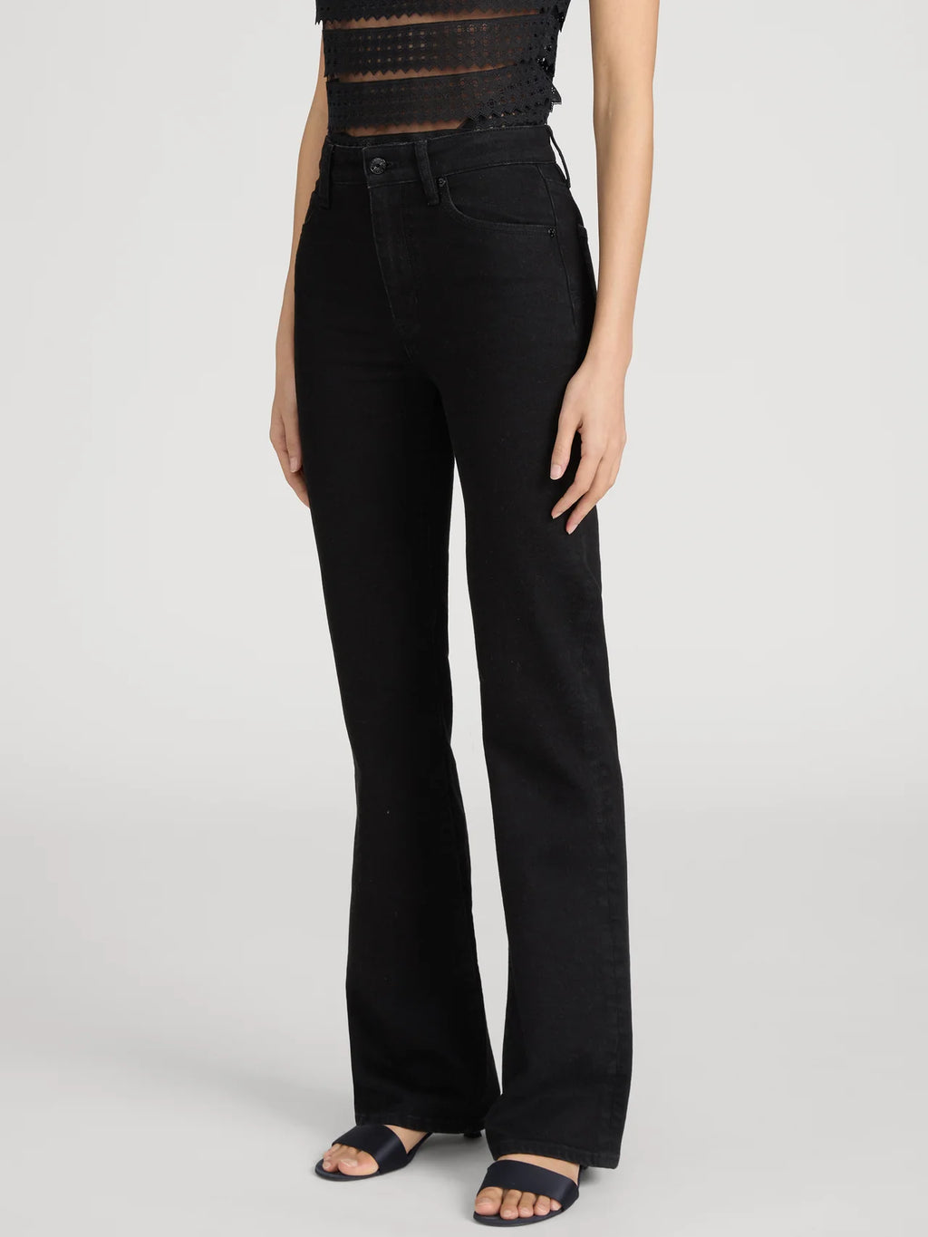 Person wearing black flared jeans on a white background