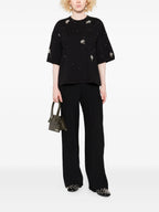 Person wearing a black outfit with floral embellishments on a white background