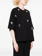 Person wearing a black top with silver embellishments on a white background