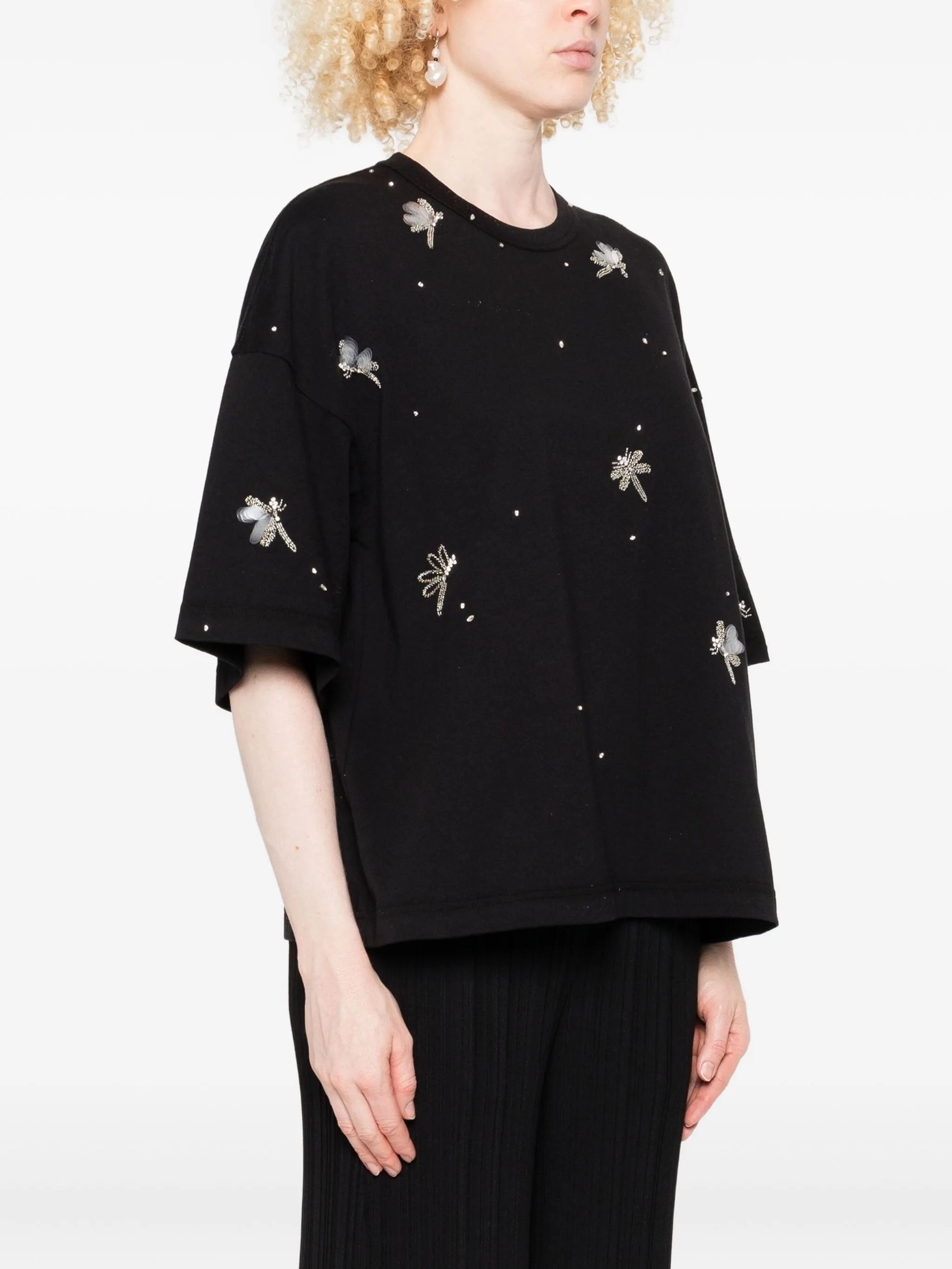 Person wearing a black top with silver embellishments on a white background