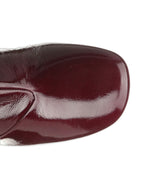 Close-up of a glossy burgundy shoe on a white background