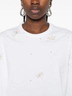 White long-sleeve shirt with small decorative patterns worn by a person on a white background