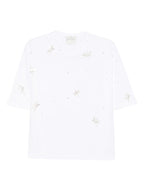 White t-shirt with small embroidered designs on a white background