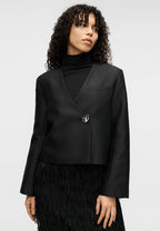 Woman wearing a black blazer with feathered skirt against a white background
