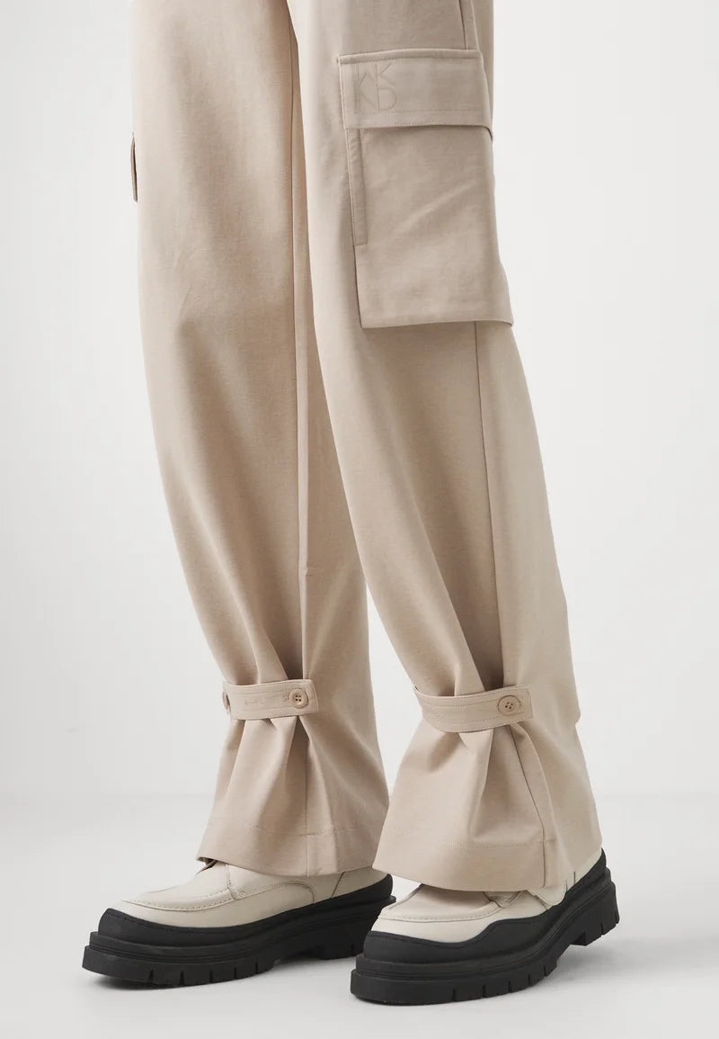 Beige cargo pants with button details on a light gray background