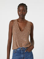 Woman wearing a sparkly brown top and blue jeans on a white background