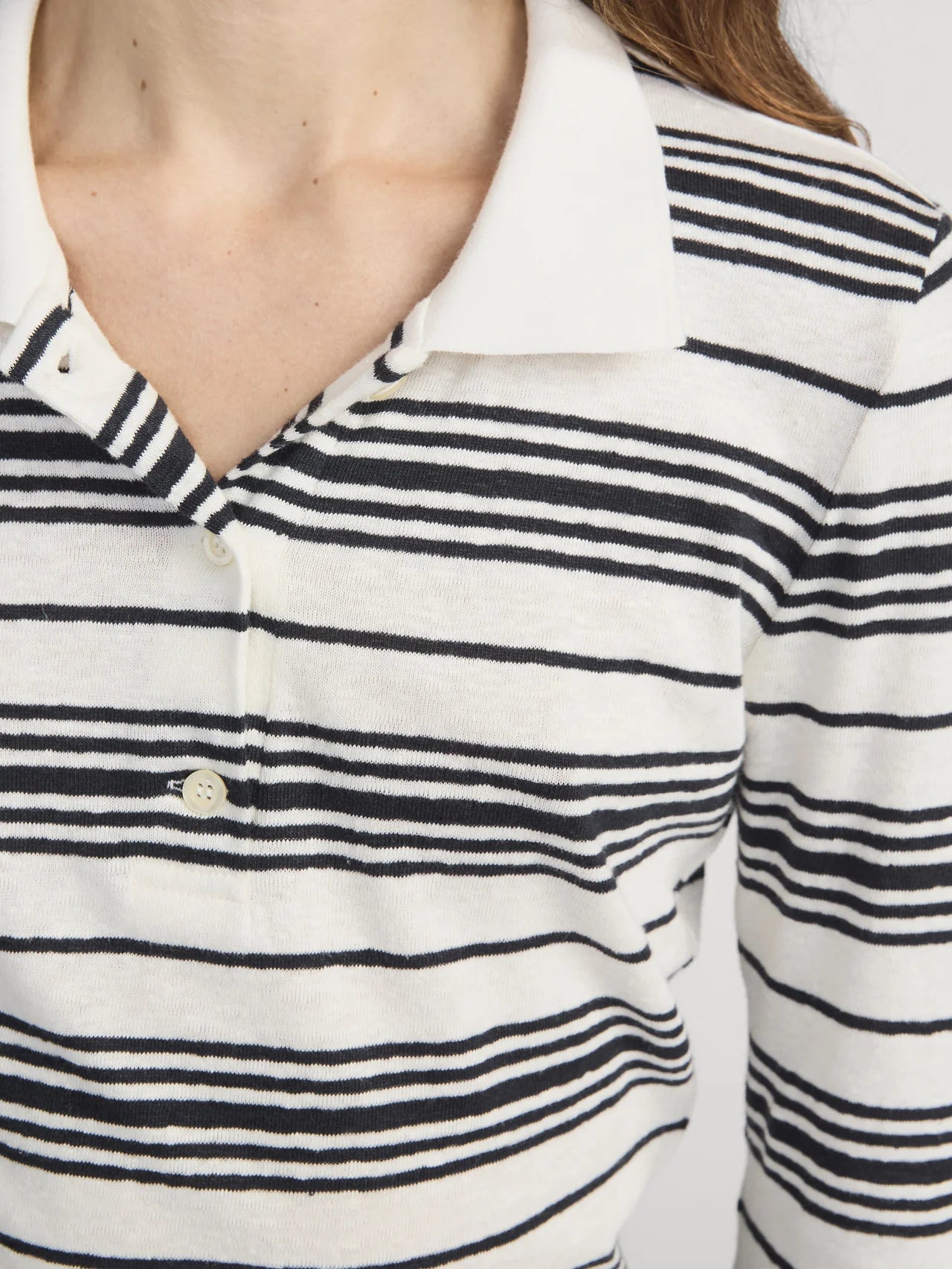 Close-up of a person wearing a white and navy striped shirt with a visible brand logo.