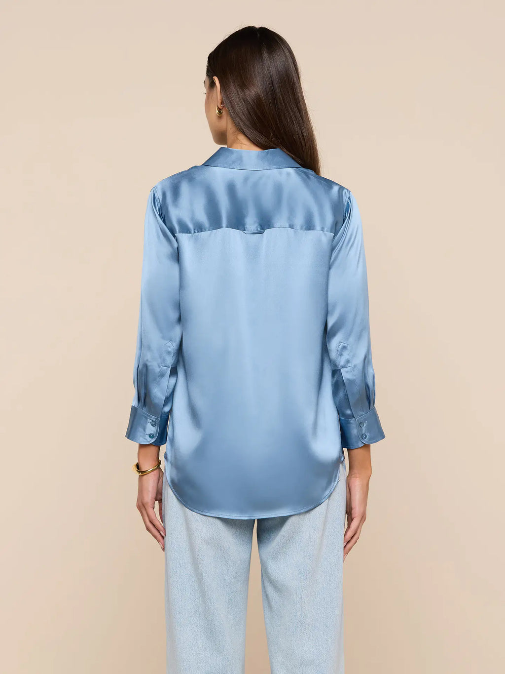 Woman wearing a light blue satin shirt on a beige background