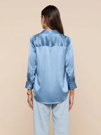 Woman wearing a light blue satin shirt on a beige background