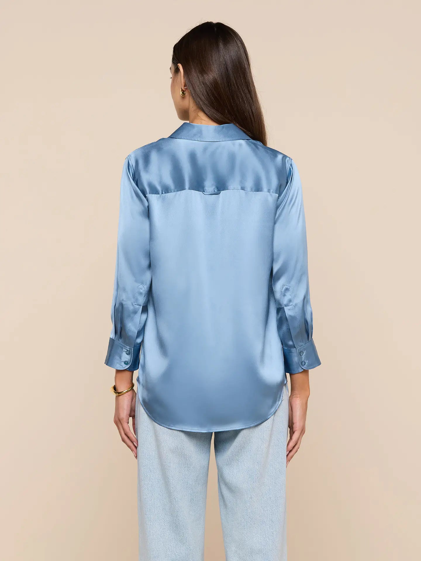 Woman wearing a light blue satin shirt on a beige background