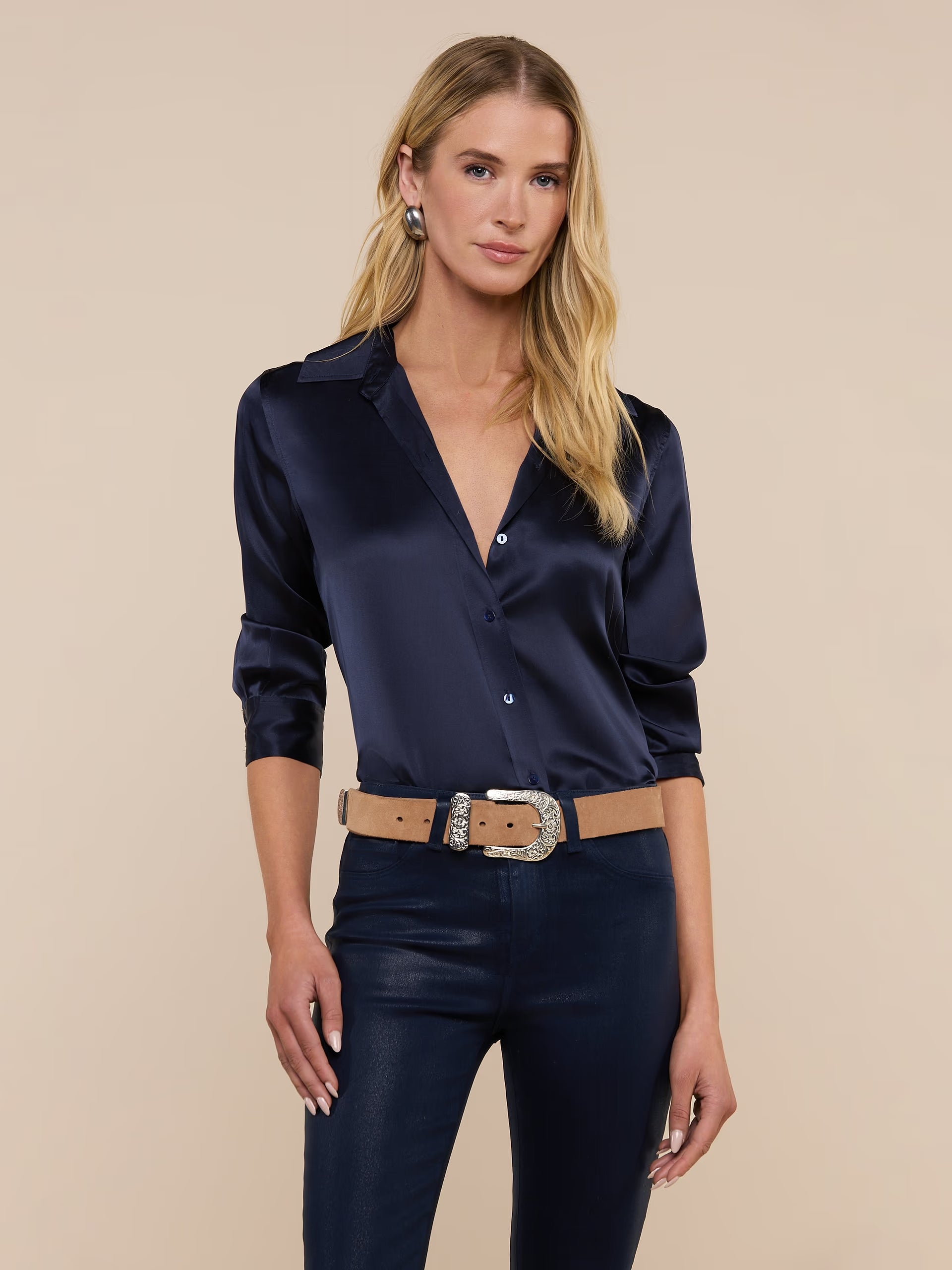 Woman wearing a navy satin shirt and pants with a beige background