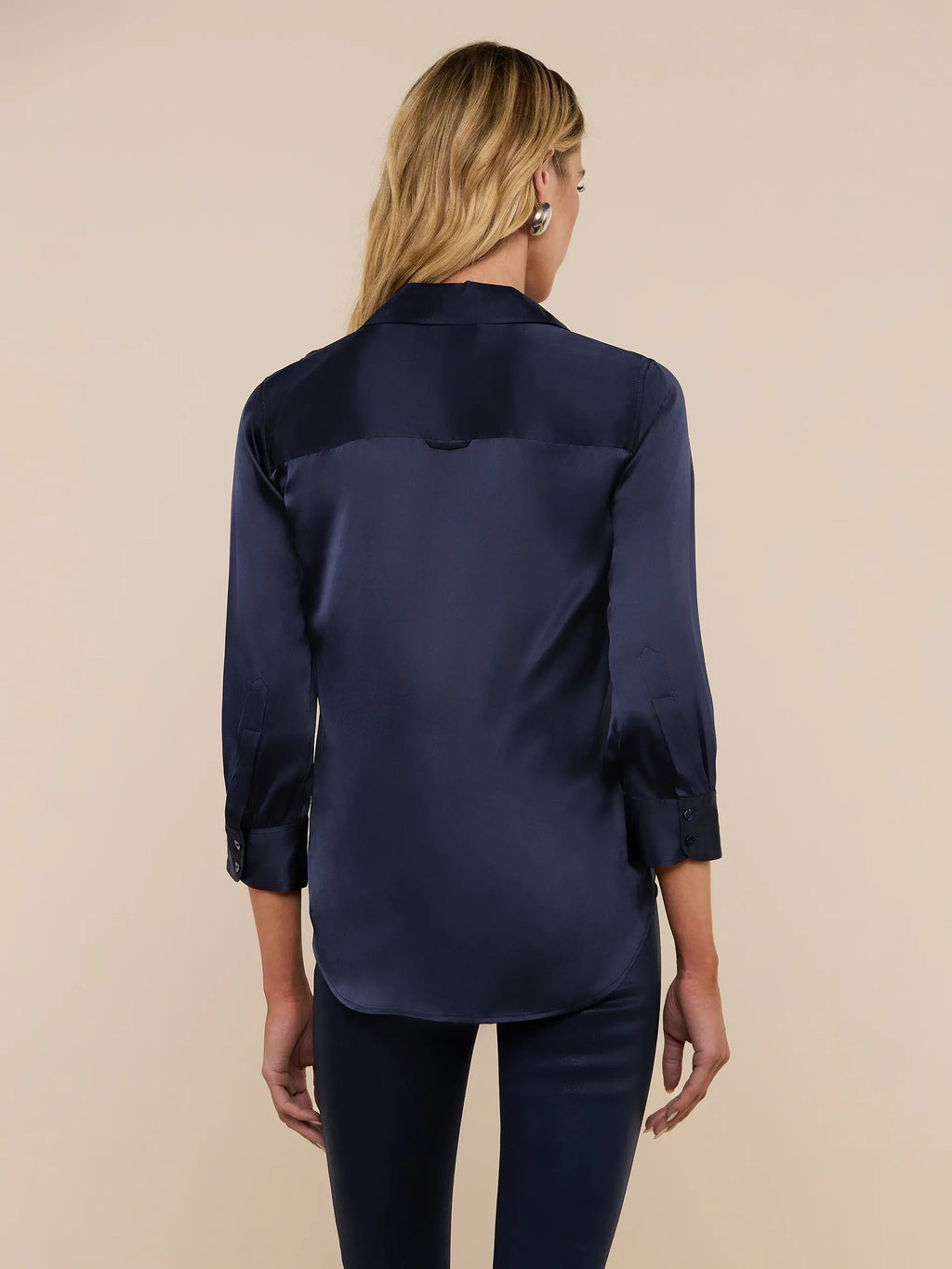 Woman wearing a navy satin shirt on a beige background