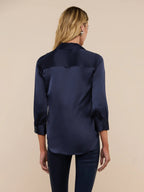 Woman wearing a navy satin shirt on a beige background