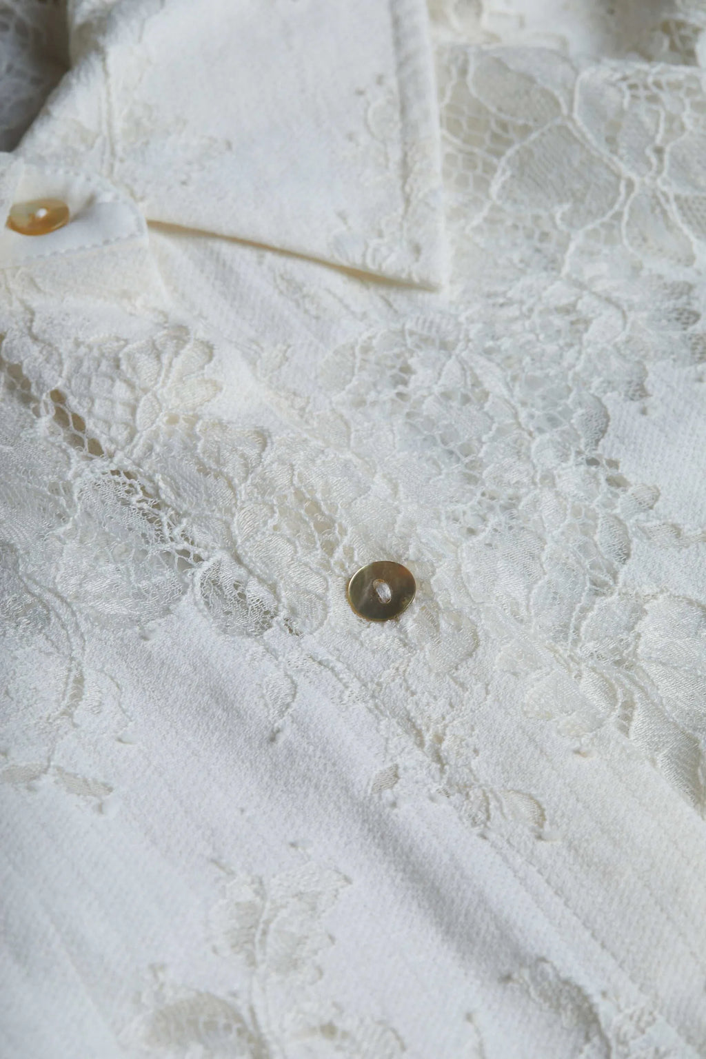 Close-up of a textured white fabric with lace details and a button.