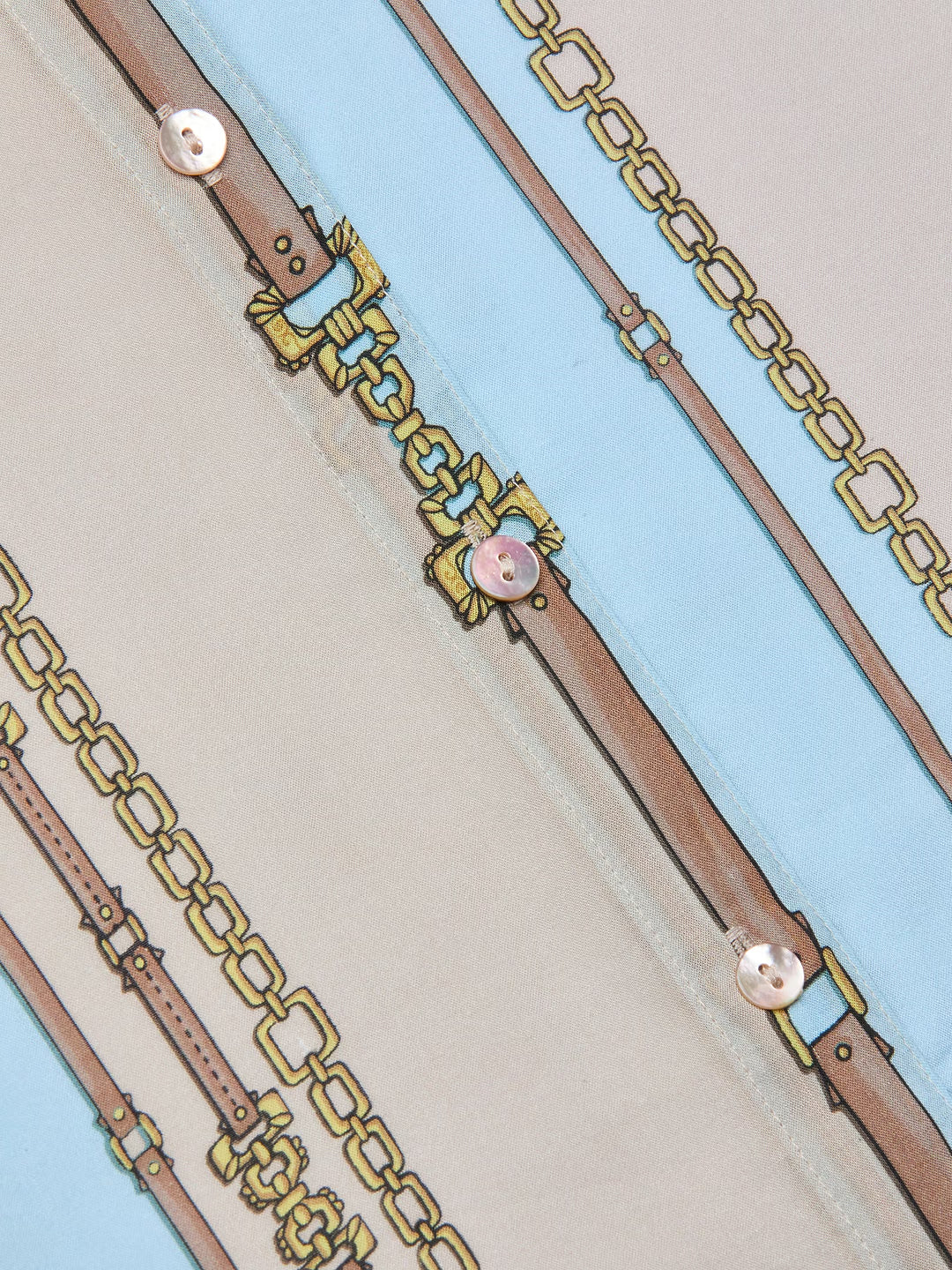 Close-up of a gold chain belt with pink buckles on a light blue background