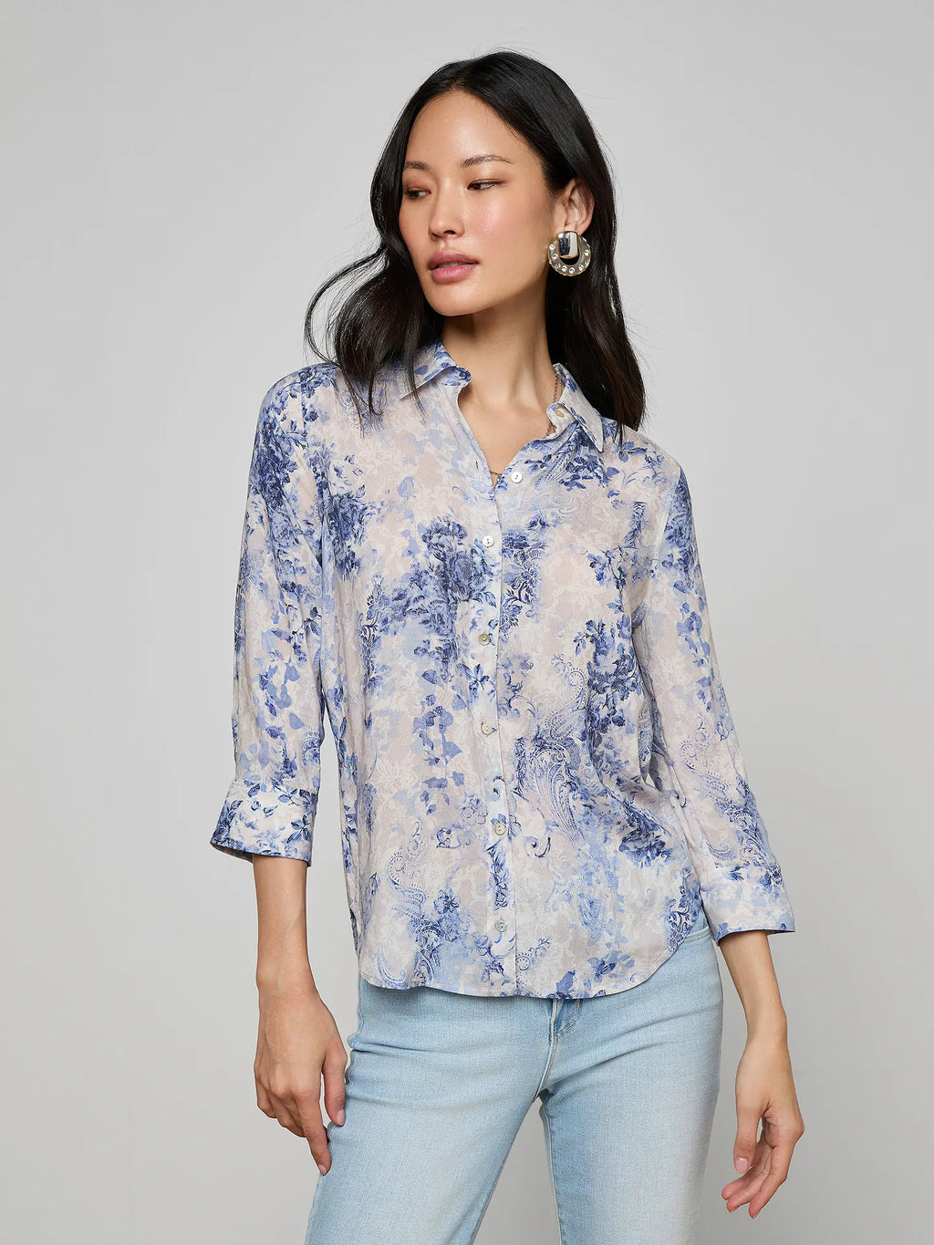 Woman wearing a blue floral blouse against a gray background