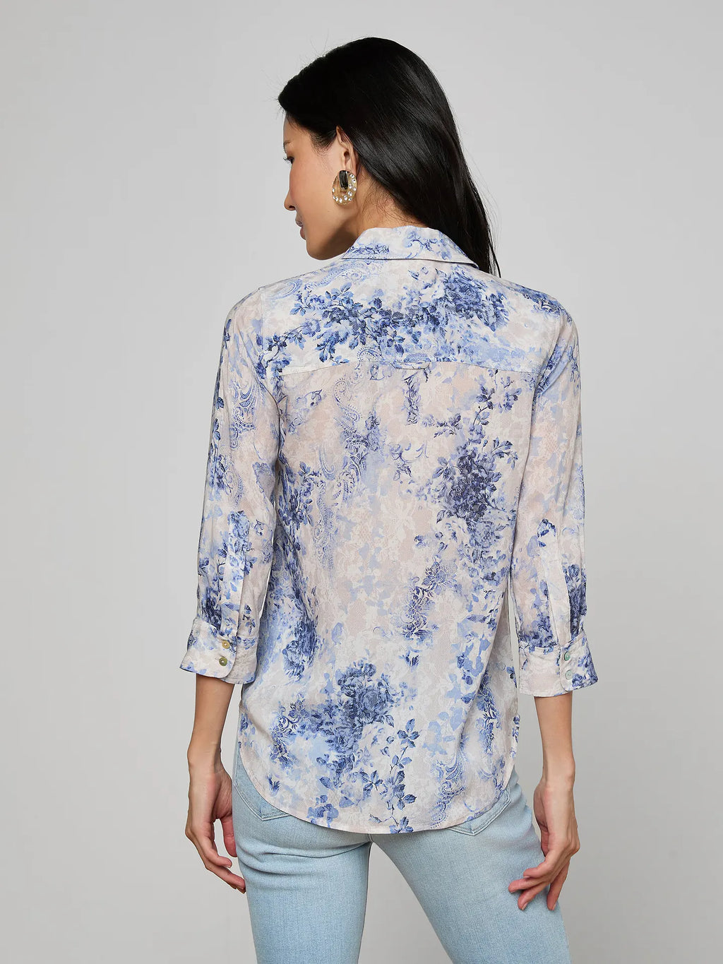 Woman wearing a floral blouse with rolled-up sleeves on a gray background