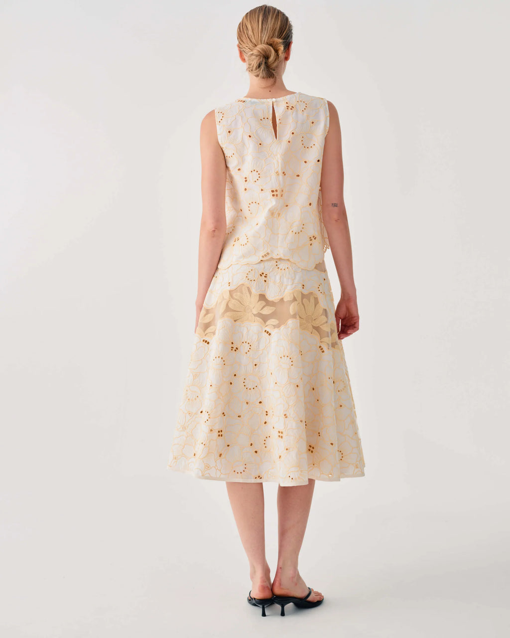 Woman wearing a cream-colored dress with floral pattern on a white background